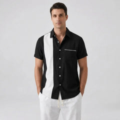 Man wearing a black and white striped shirt with white pants on a gray background