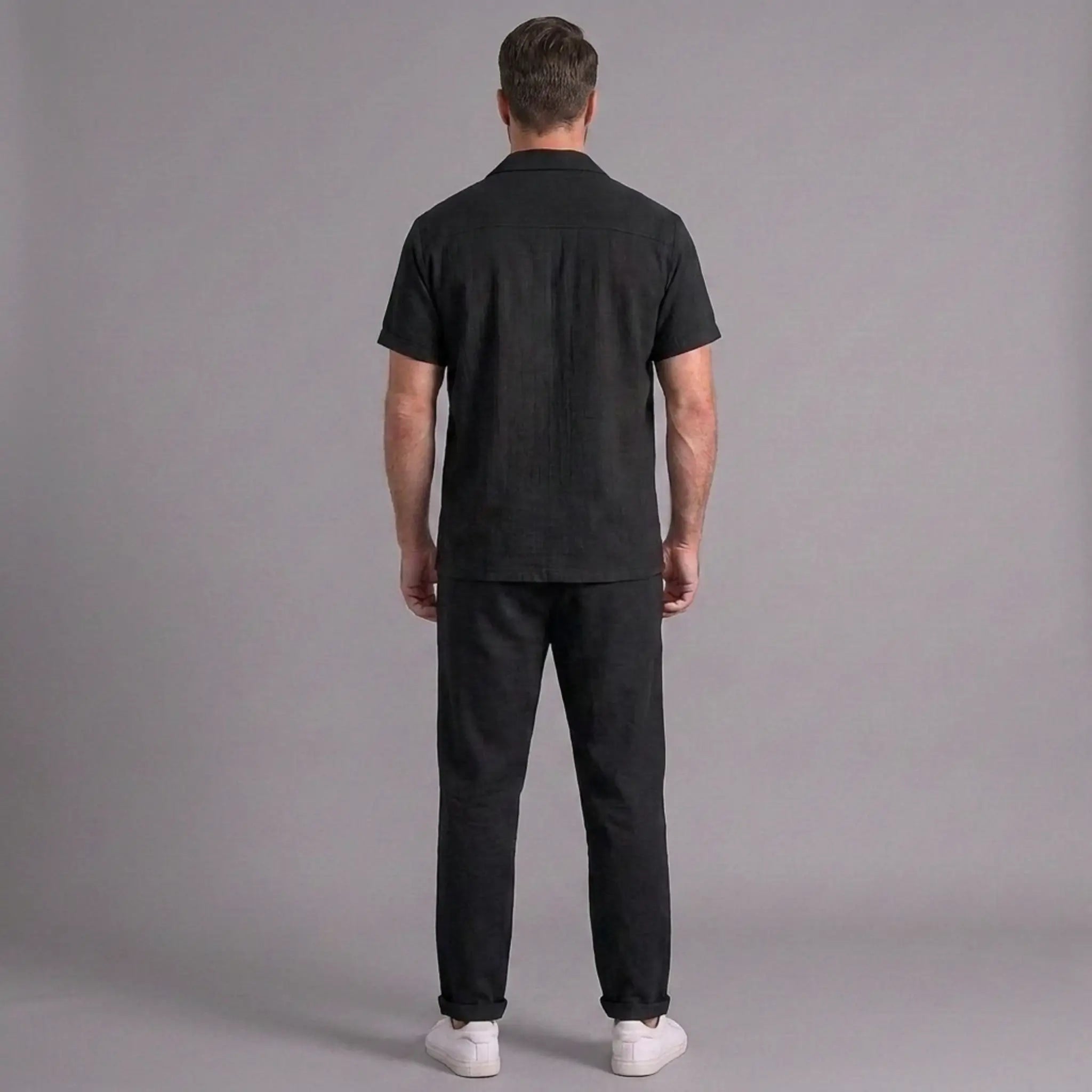 Man wearing a black outfit against a gray background