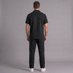 Man wearing a black outfit against a gray background
