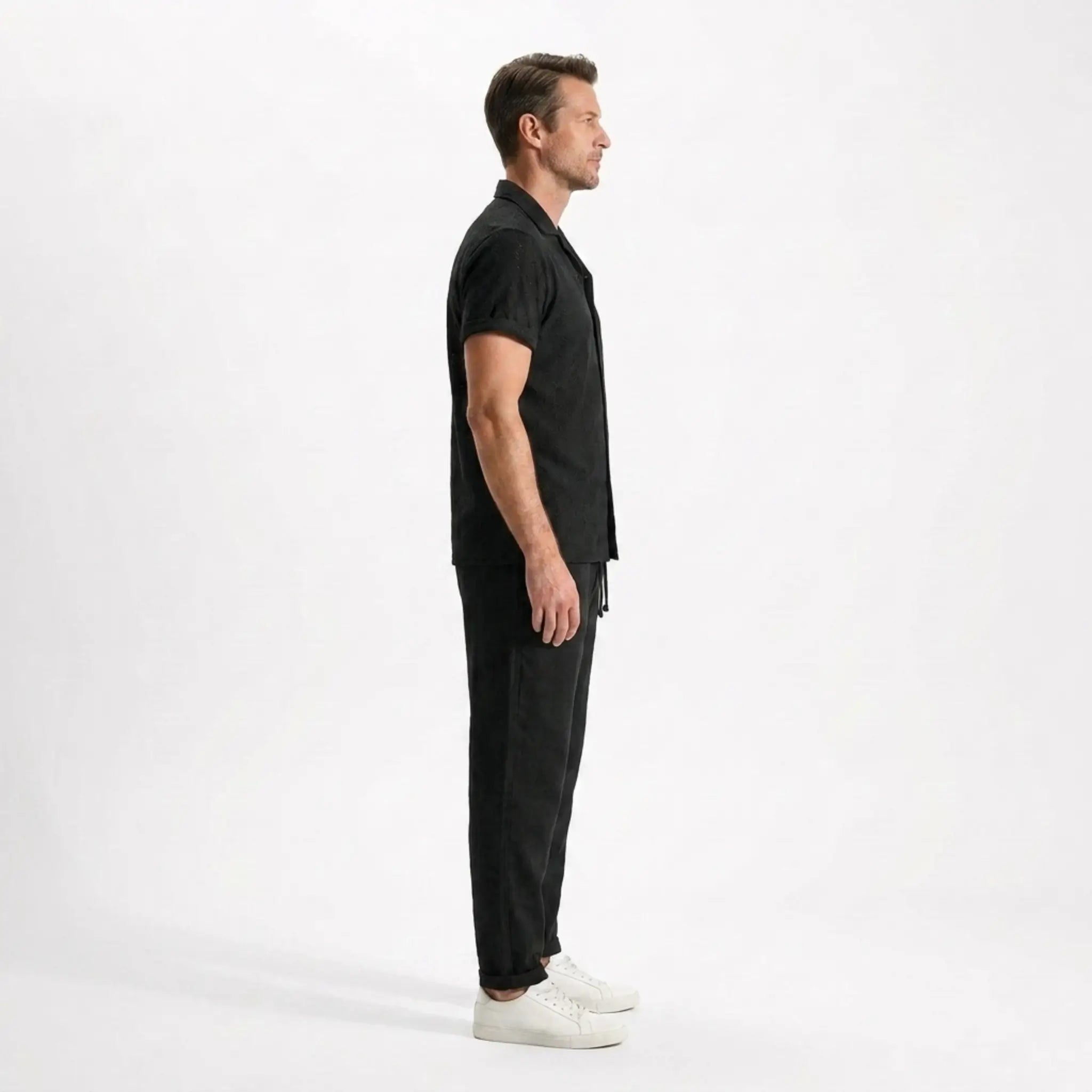 Man wearing a black outfit side view on a white background