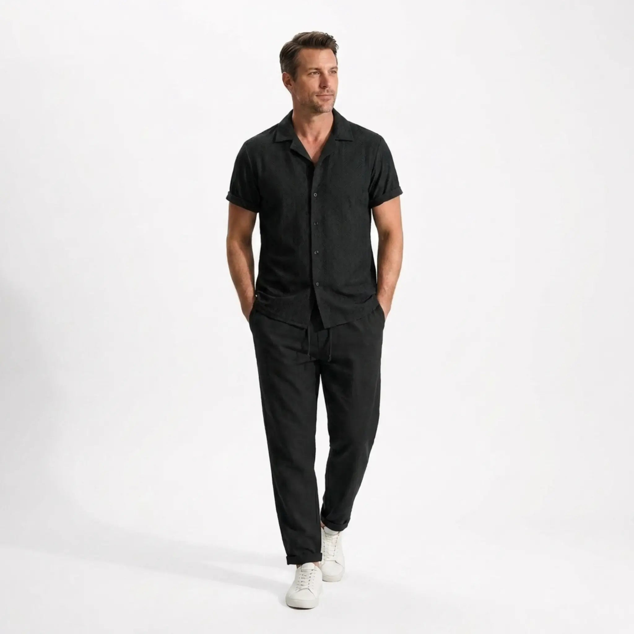 Man wearing a black outfit with white shoes on a white background