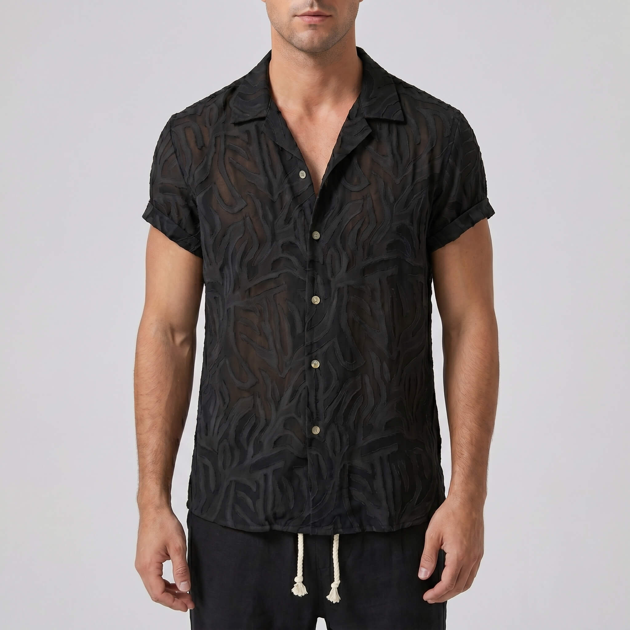 Man wearing a black patterned shirt against a plain background
