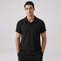 Man wearing a black polo shirt and pants on a light gray front shirt view background