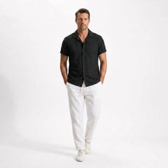 Man wearing a black shirt and white pants on a white background
