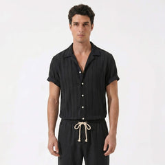 Man wearing a black striped shirt with white buttons and black pants with a drawstring on a white background