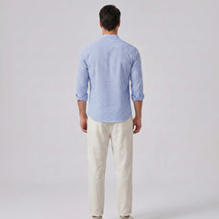 Man wearing a blue checkered shirt and white pants on a light gray background