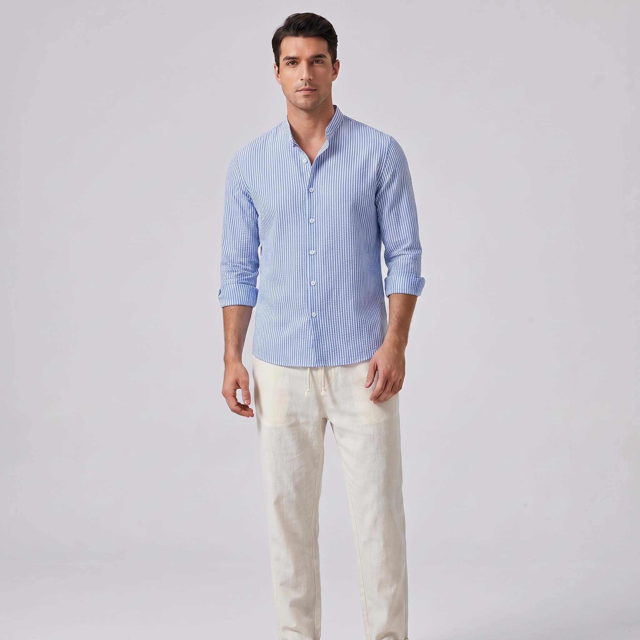 Man wearing a blue striped shirt and light-colored pants on a gray background