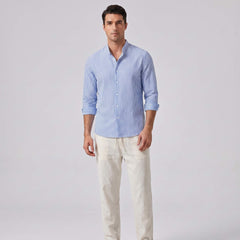 Man wearing a blue striped shirt and light-colored pants on a gray background