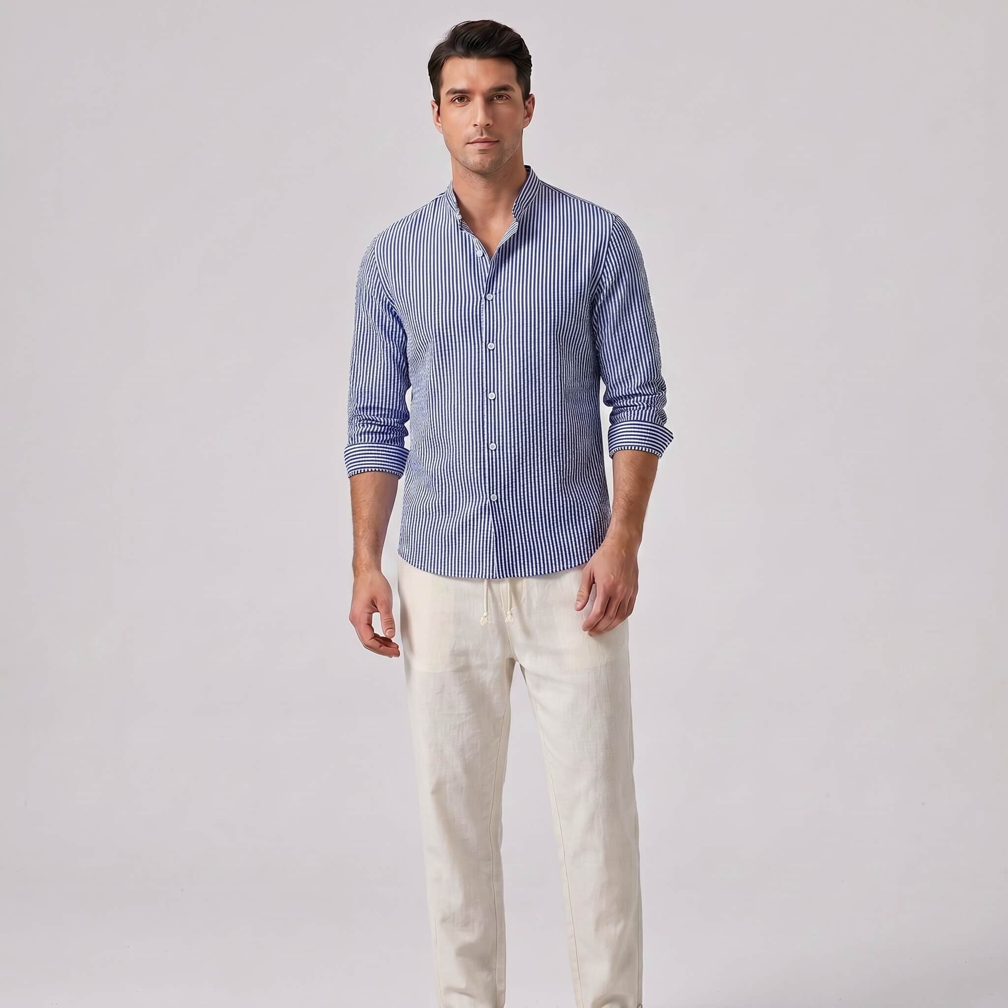 Man wearing a blue striped shirt and white pants on a gray background
