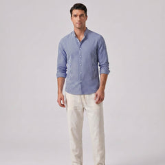 Man wearing a blue striped shirt and white pants on a gray background