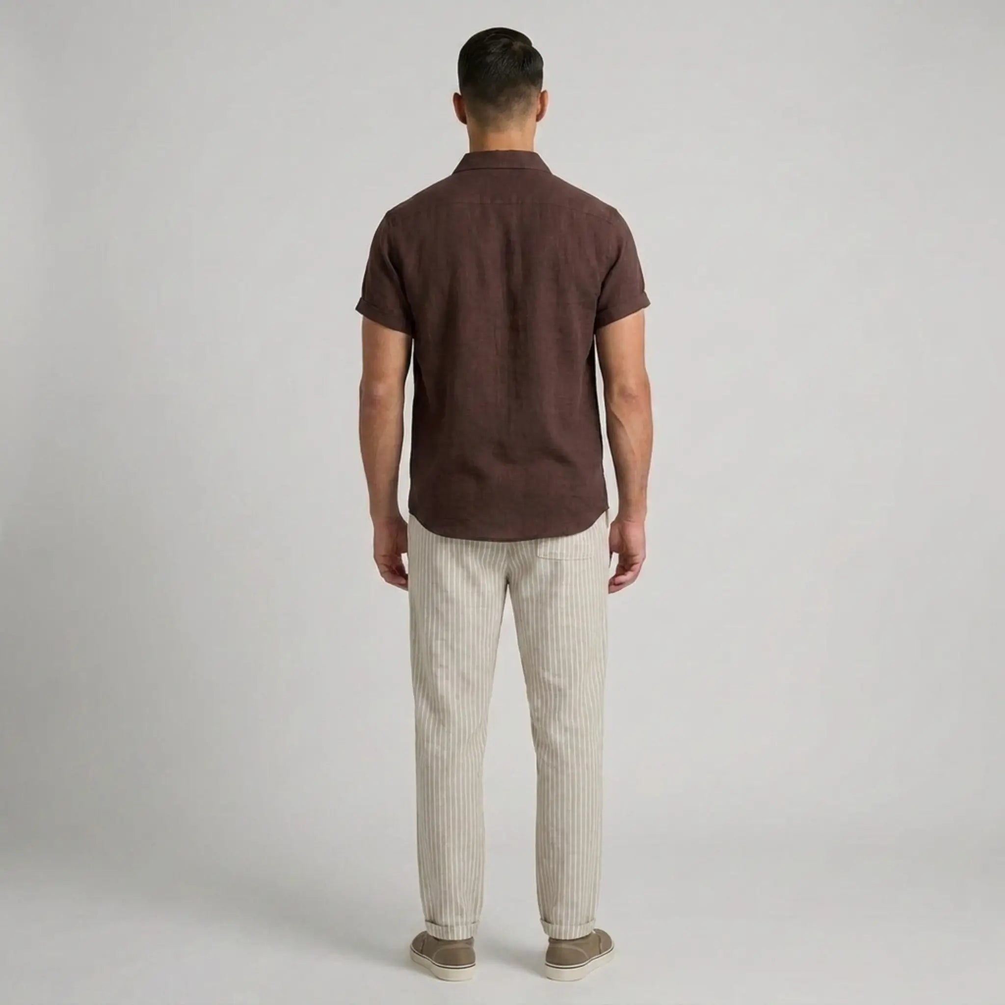 Man wearing a brown polo shirt and beige pants on a plain background