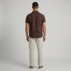 Man wearing a brown polo shirt and beige pants on a plain background