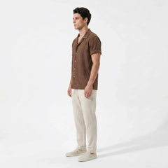 Man wearing a brown short-sleeve shirt and beige pants on a white background