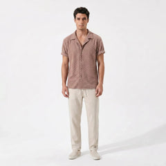 Man wearing a brown textured shirt and beige pants on a white background