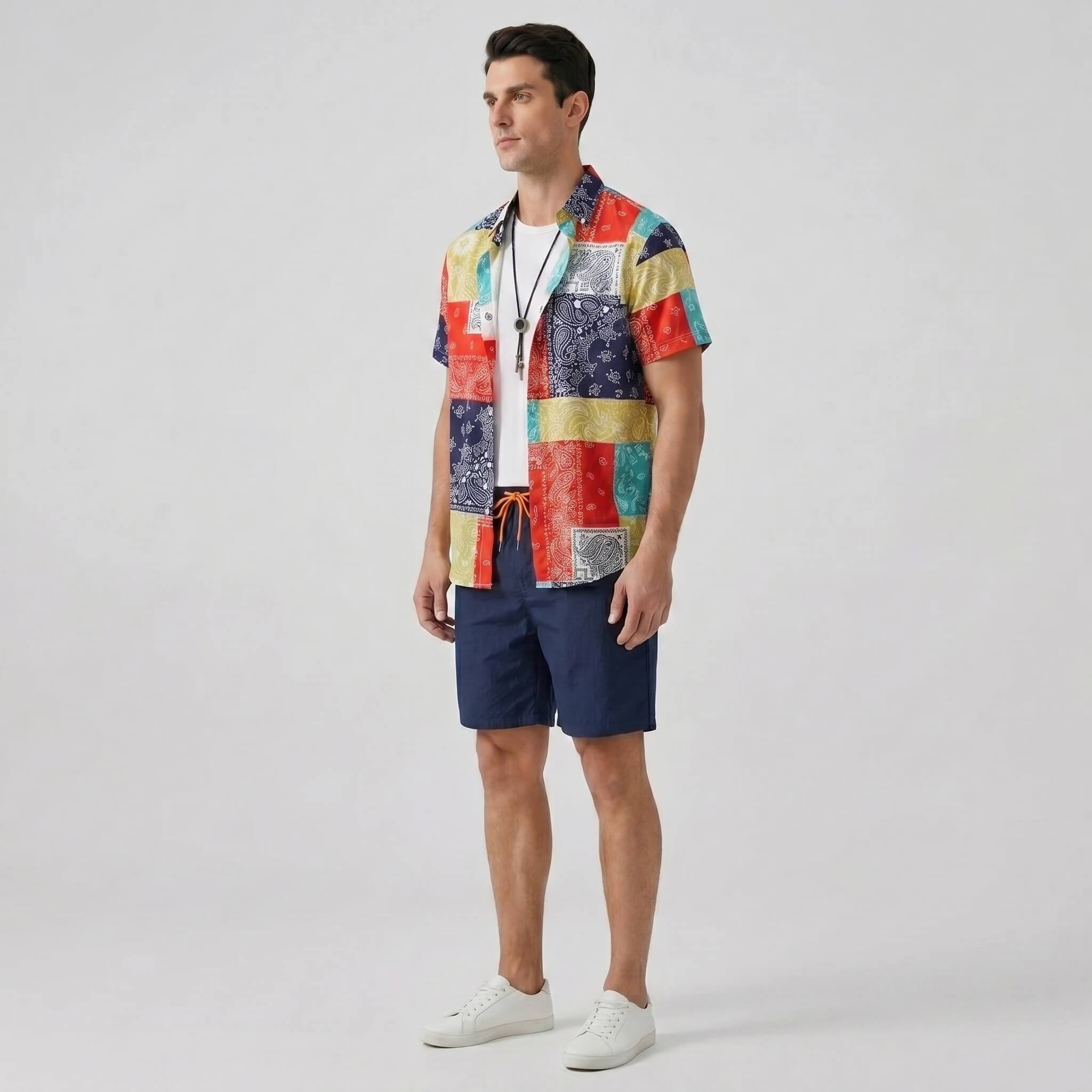 Man wearing a colorful patterned shirt and navy shorts side view on a light gray background