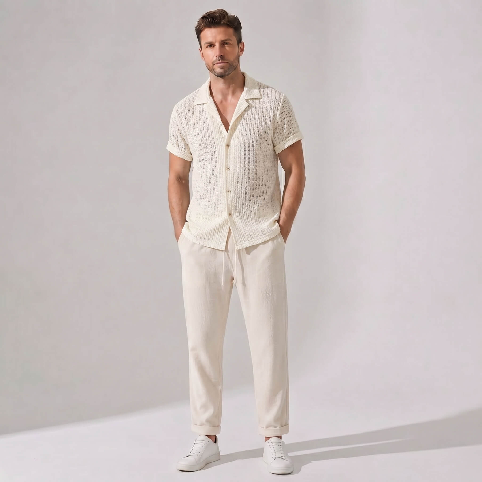 Man wearing a cream-colored outfit with a shirt and pants on a plain background