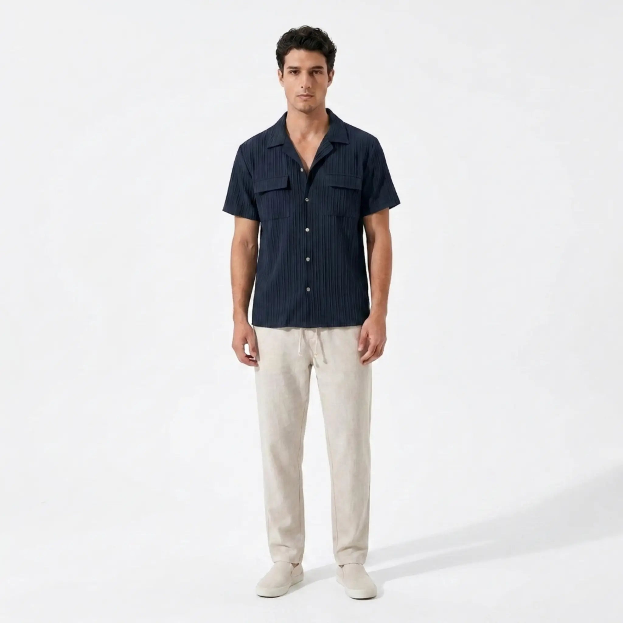 Man wearing a dark blue shirt and beige pants on a white background
