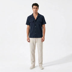Man wearing a dark blue shirt and beige pants on a white background