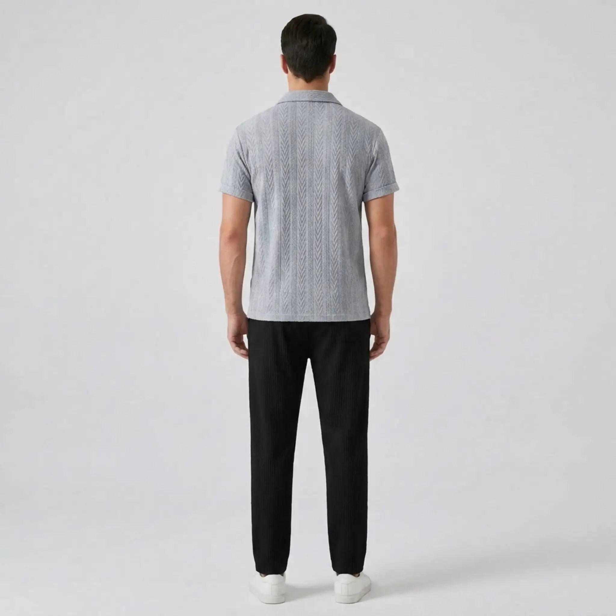 Man wearing a gray patterned polo shirt and black pants back view on a white background