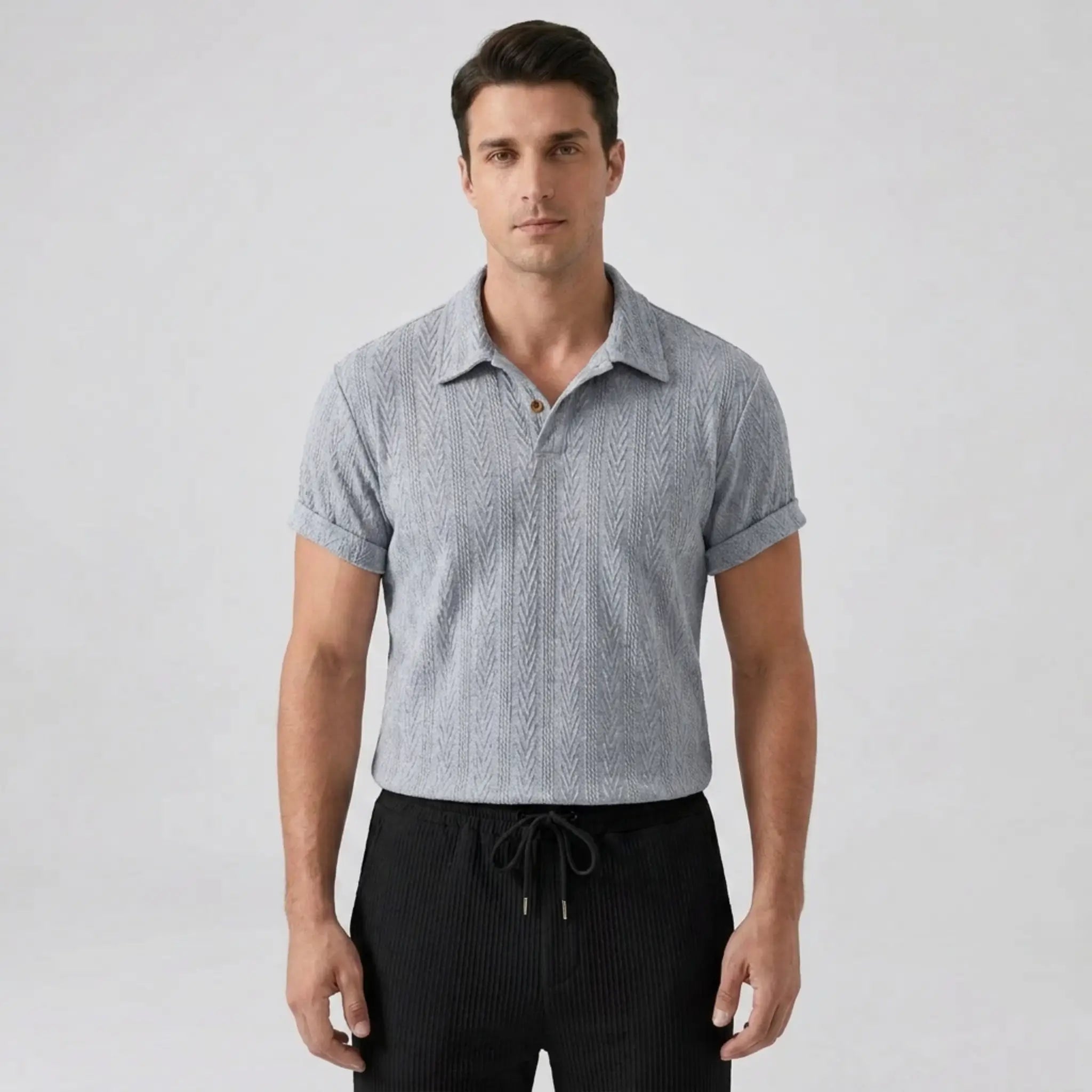 Man wearing a gray patterned short-sleeve shirt and black pants on a light gray background