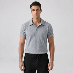 Man wearing a gray patterned short-sleeve shirt and black pants on a light gray background