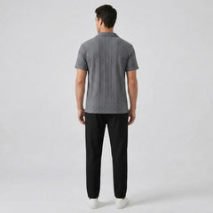 Man wearing a gray polo shirt and black pants on a white background