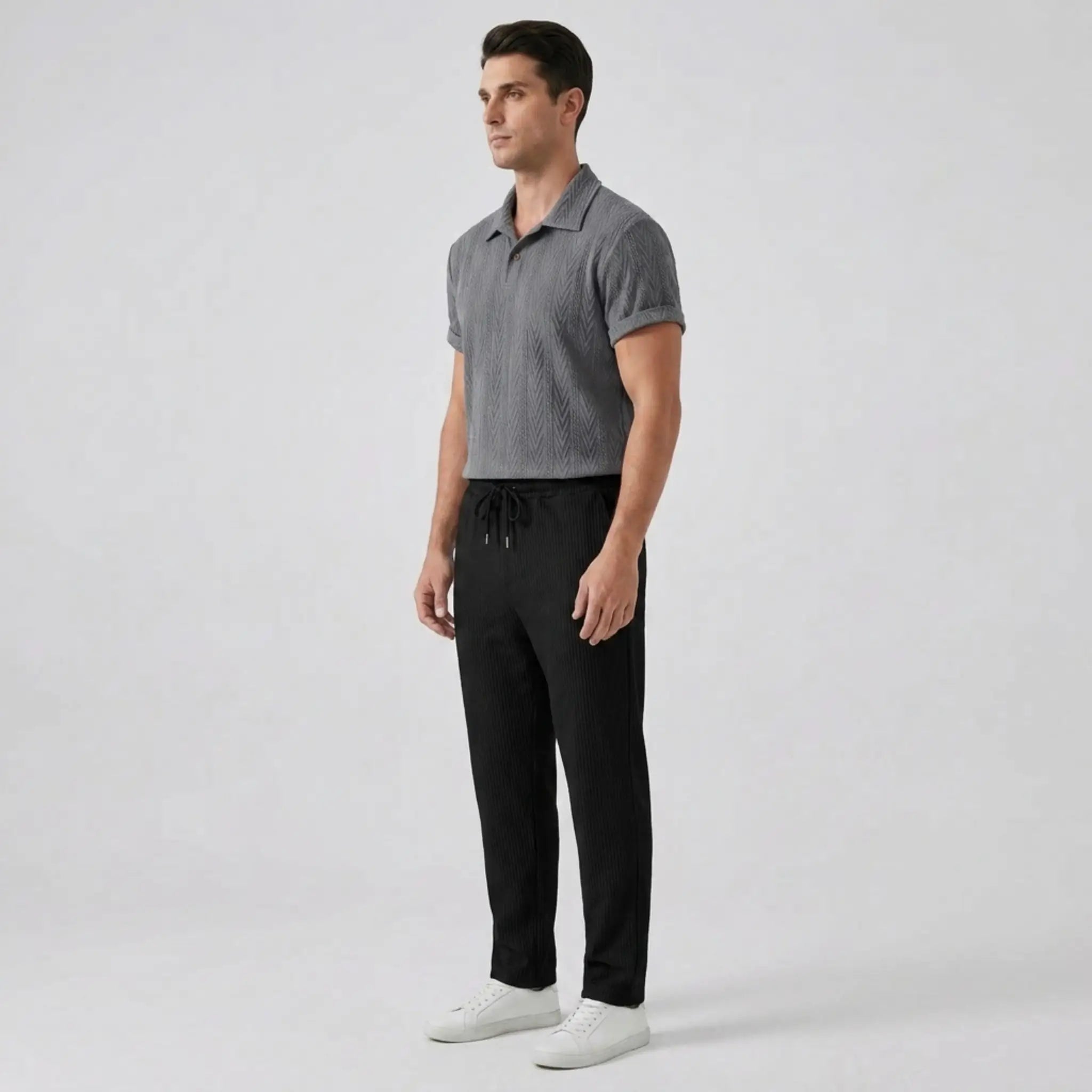 Man wearing a gray textured polo shirt and black pants on a white background