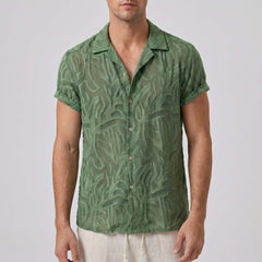 Man wearing a green patterned shirt against a plain background