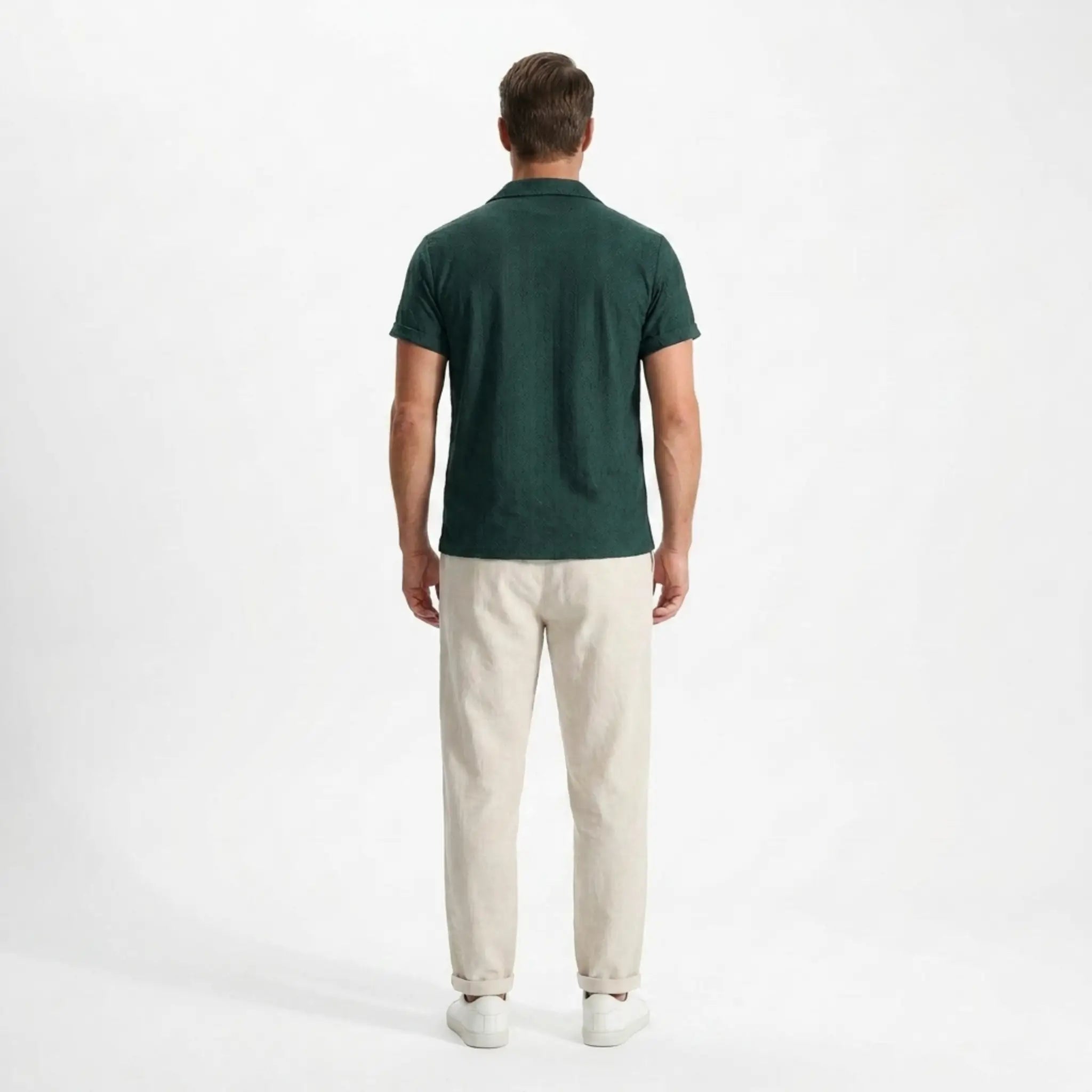Man wearing a green polo shirt and beige pants back view on a white background