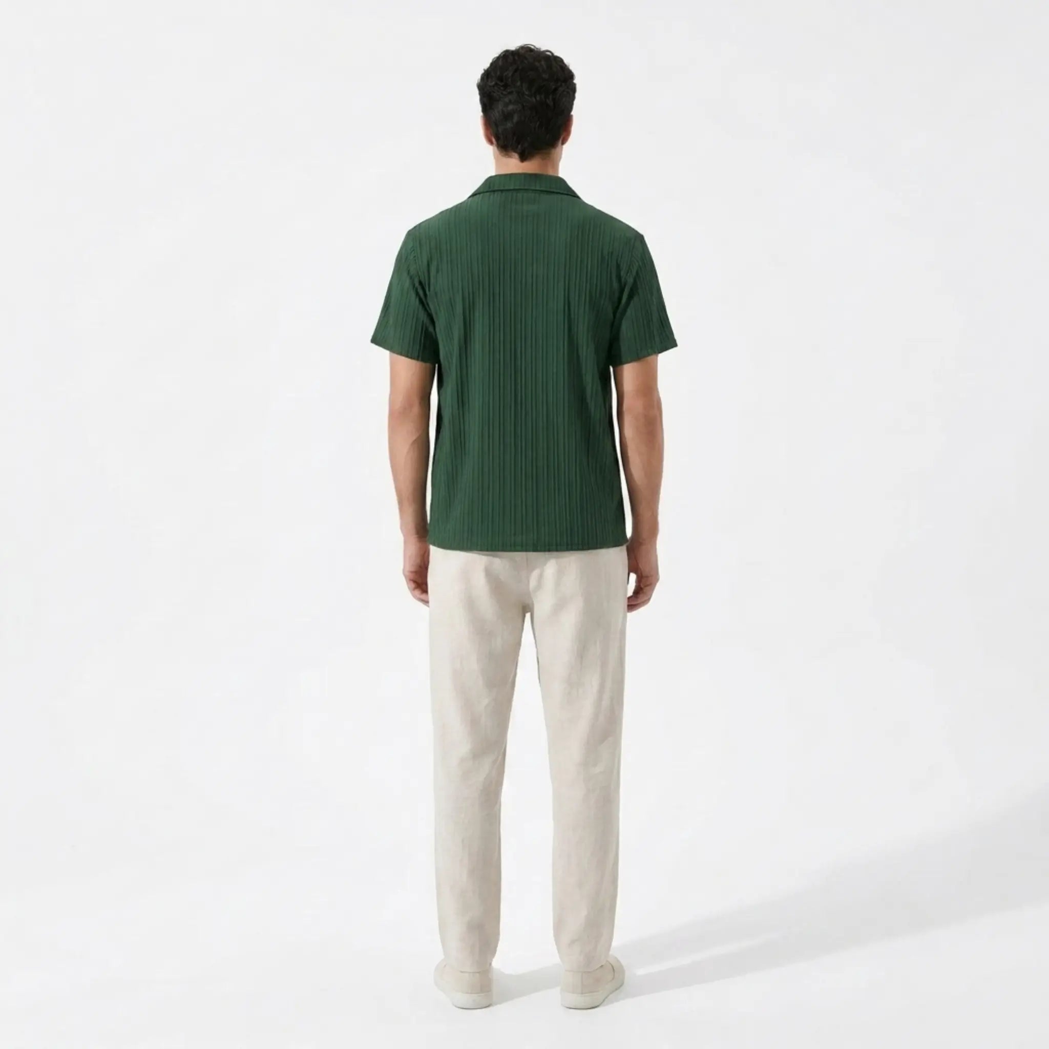 Man wearing a green polo shirt and beige pants on a white background