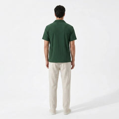 Man wearing a green polo shirt and beige pants on a white background