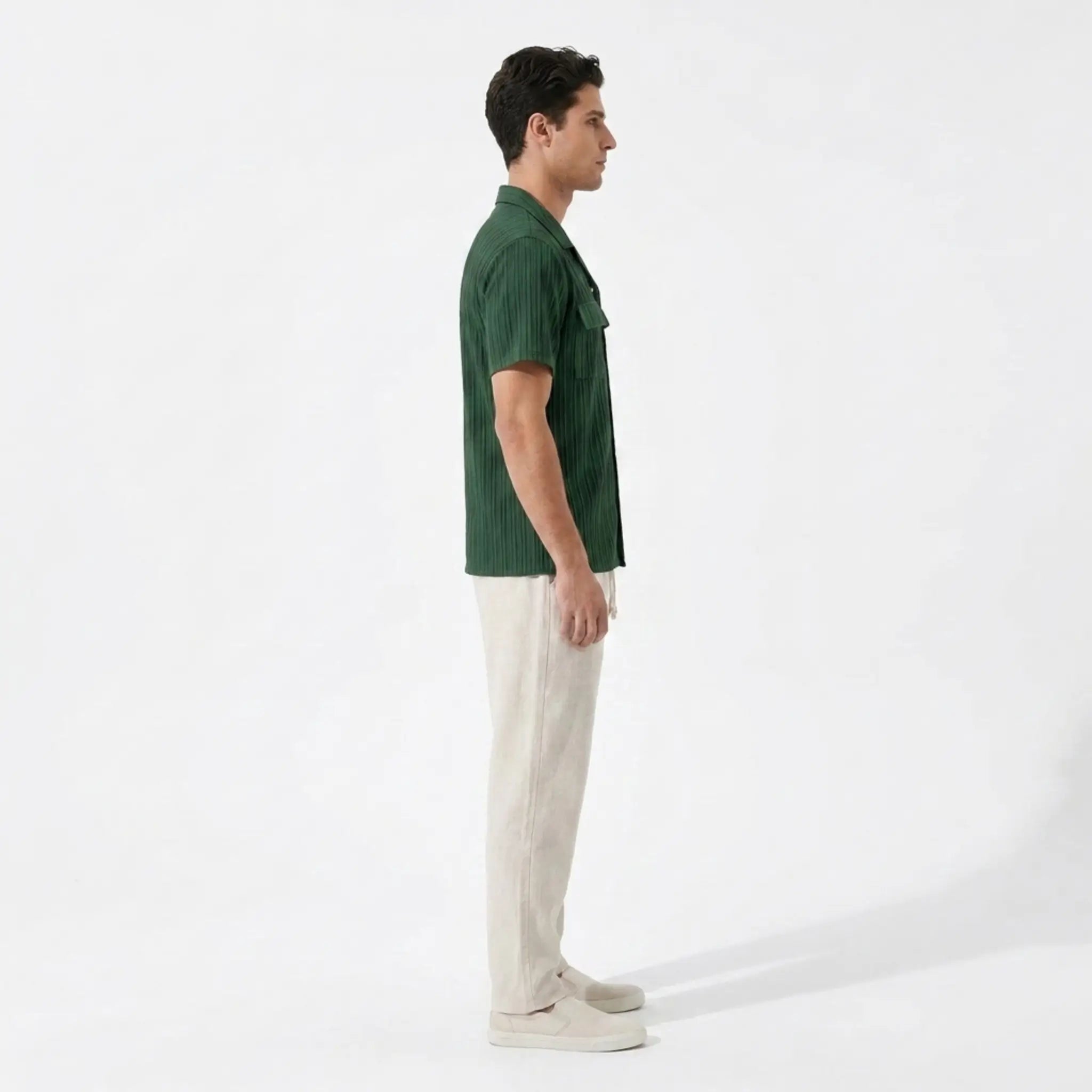 Man wearing a green polo shirt and beige pants on a white background