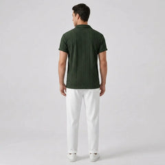 Man wearing a green polo shirt and white pants back view on a light gray background