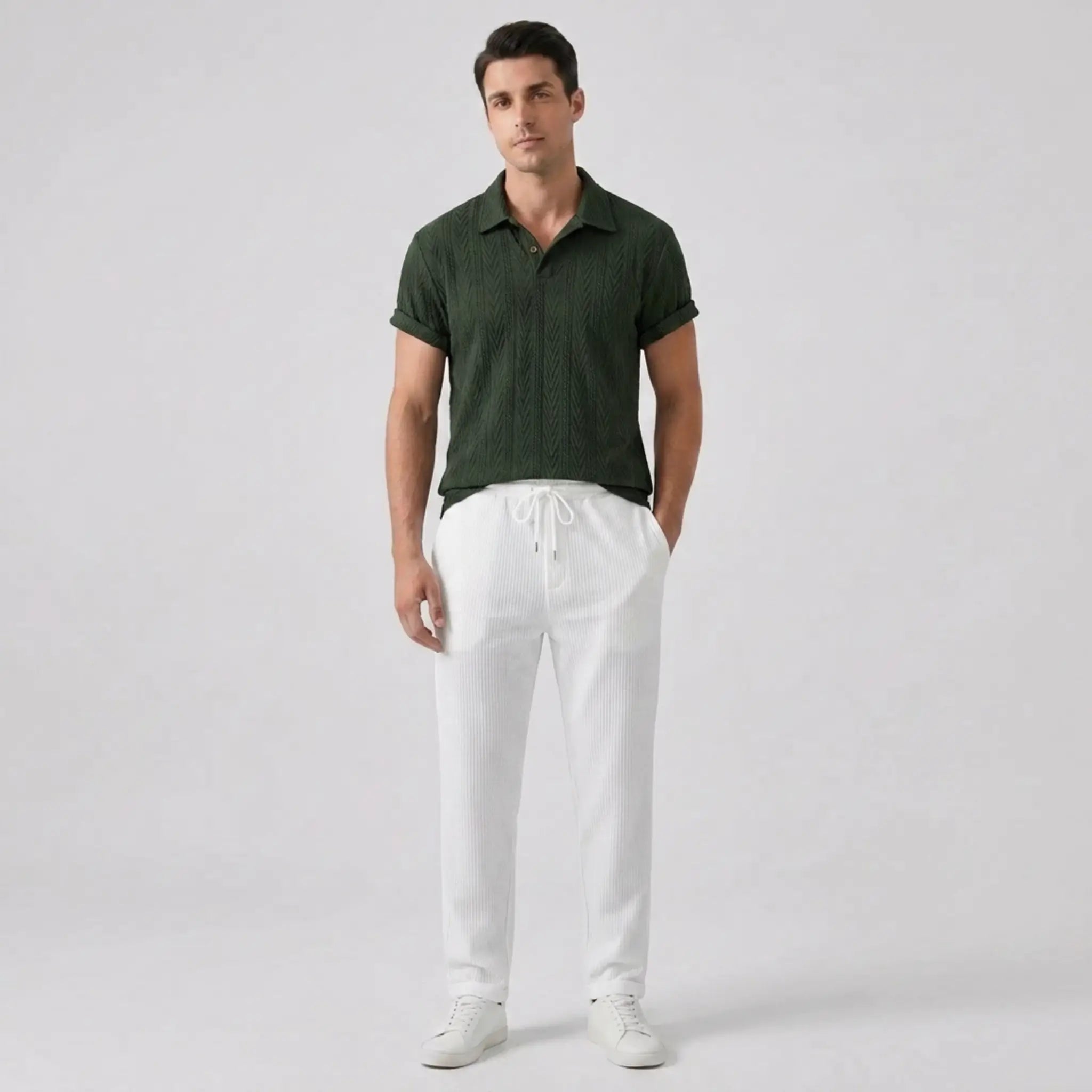 Man wearing a green polo shirt and white pants on a light gray background