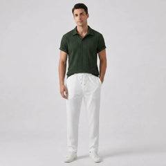 Man wearing a green polo shirt and white pants on a light gray background