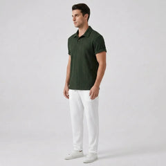 Man wearing a green polo shirt and white pants side view on a light gray background
