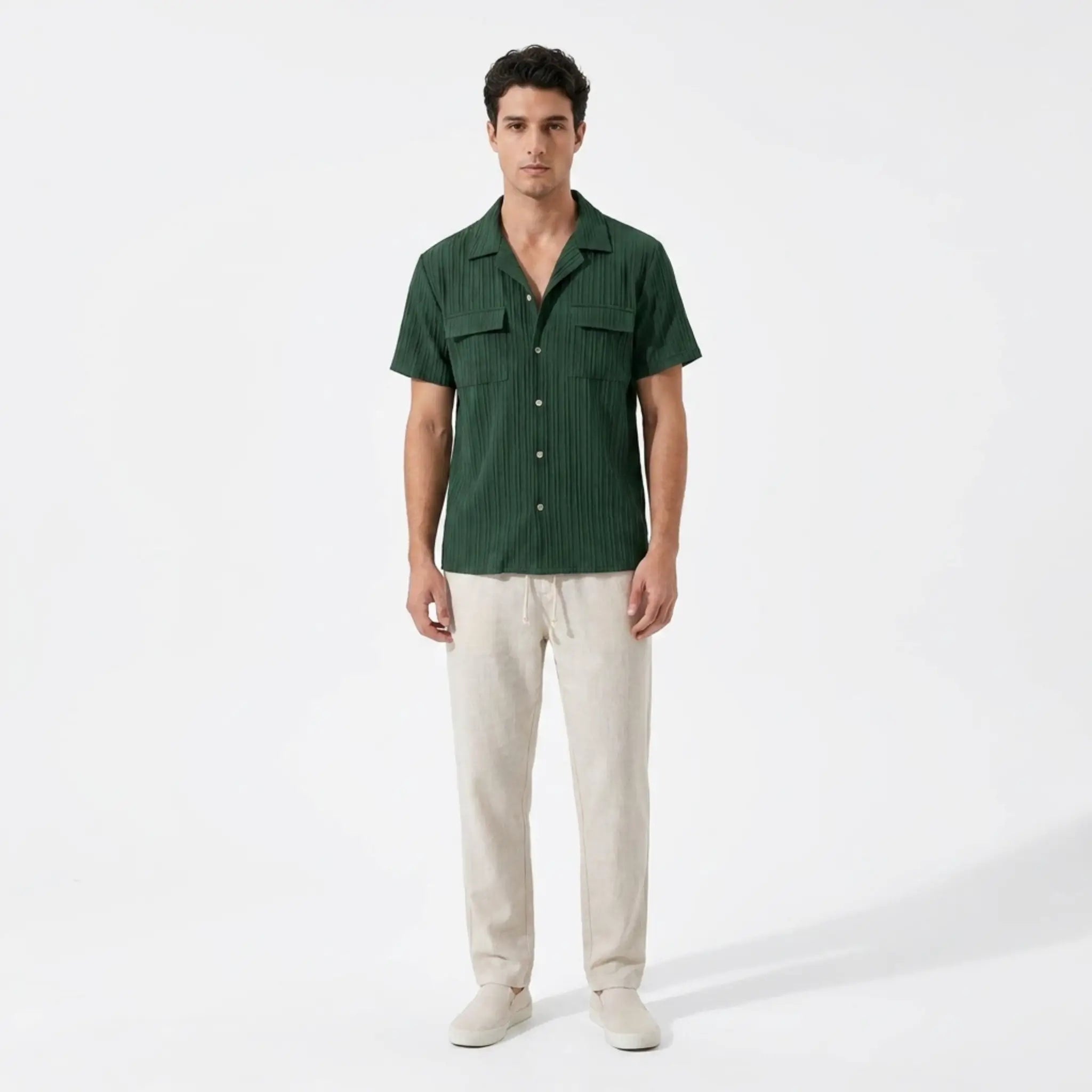 Man wearing a green shirt and beige pants on a white background