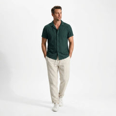 Man wearing a green shirt and beige pants on a white background