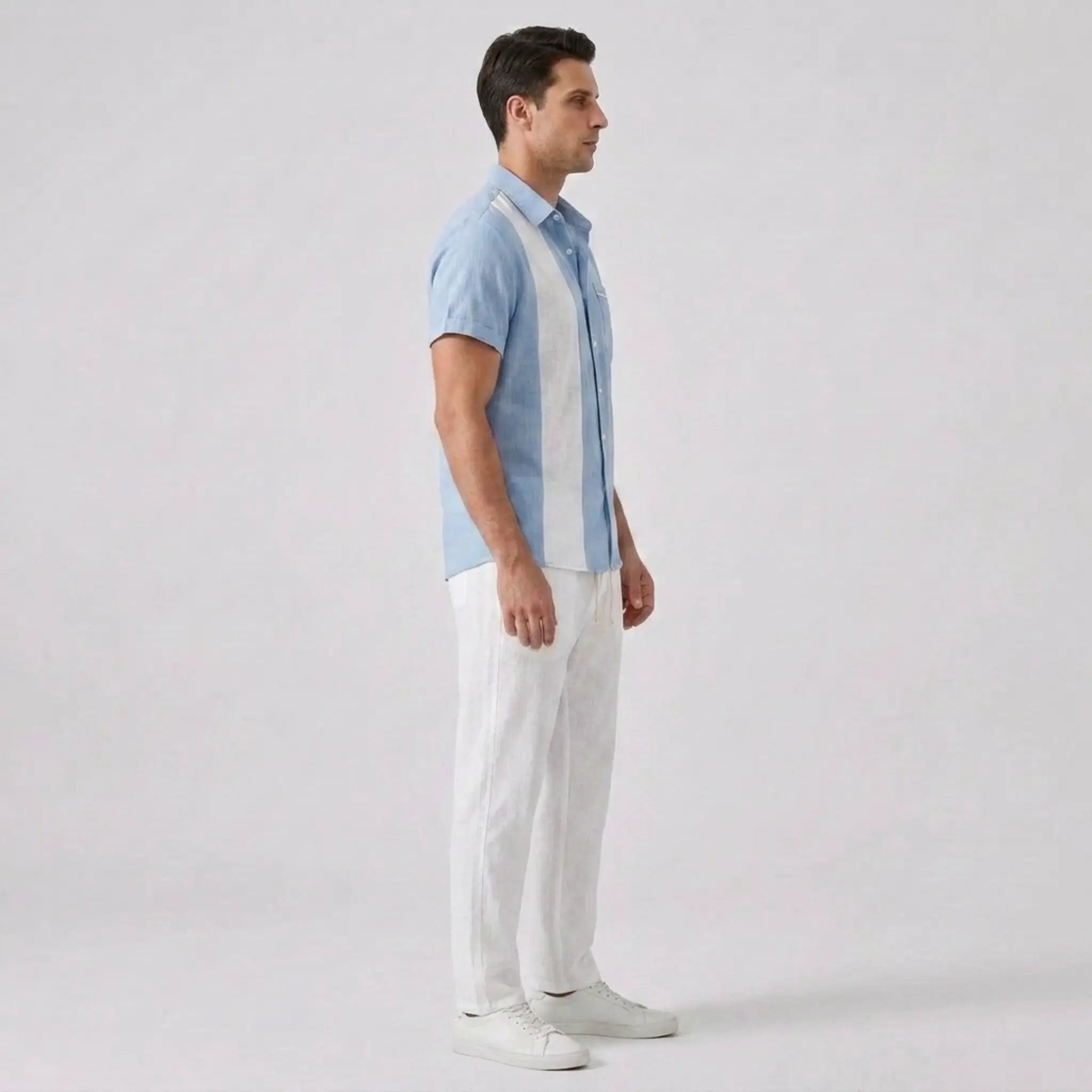 Man wearing a light blue and white striped shirt with white pants on a plain background