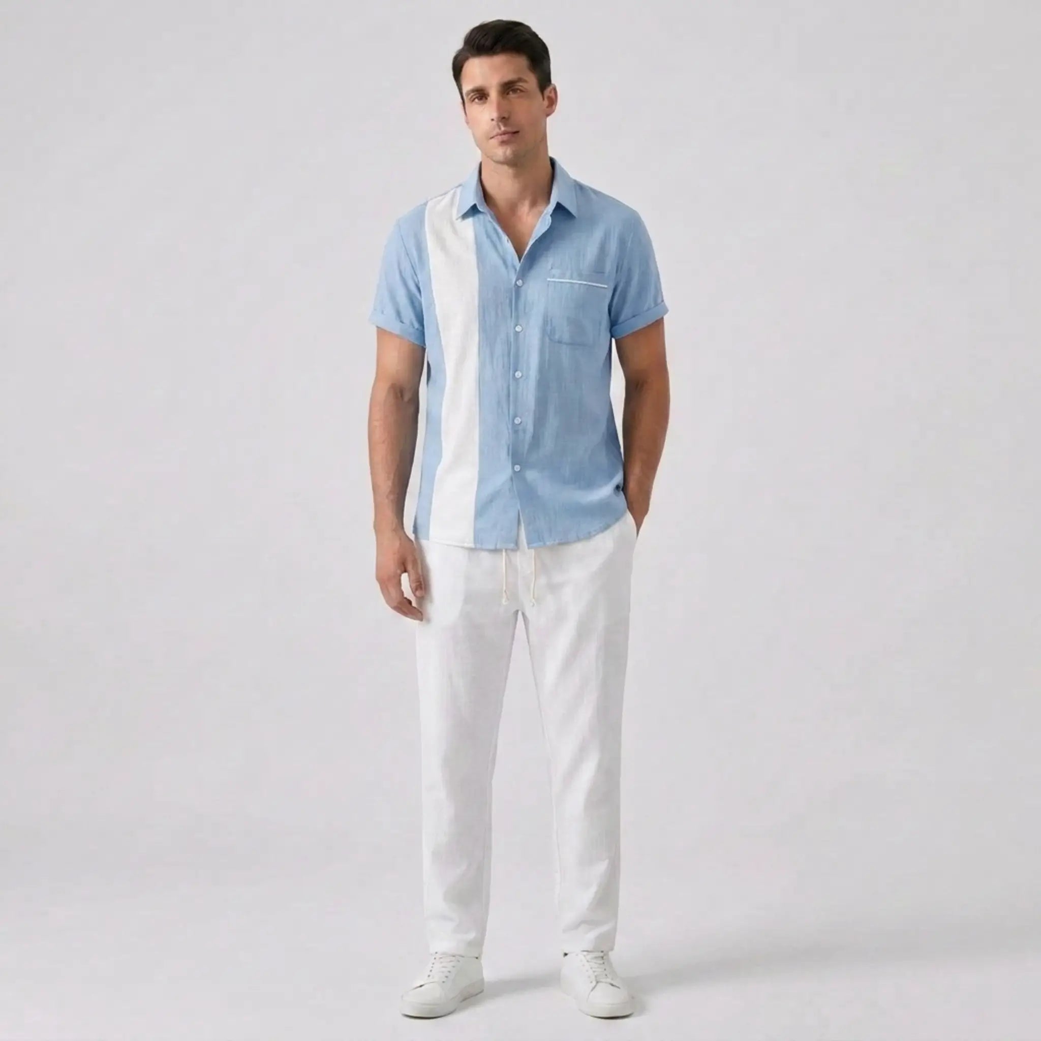 Man wearing a light blue shirt and white pants on a gray background