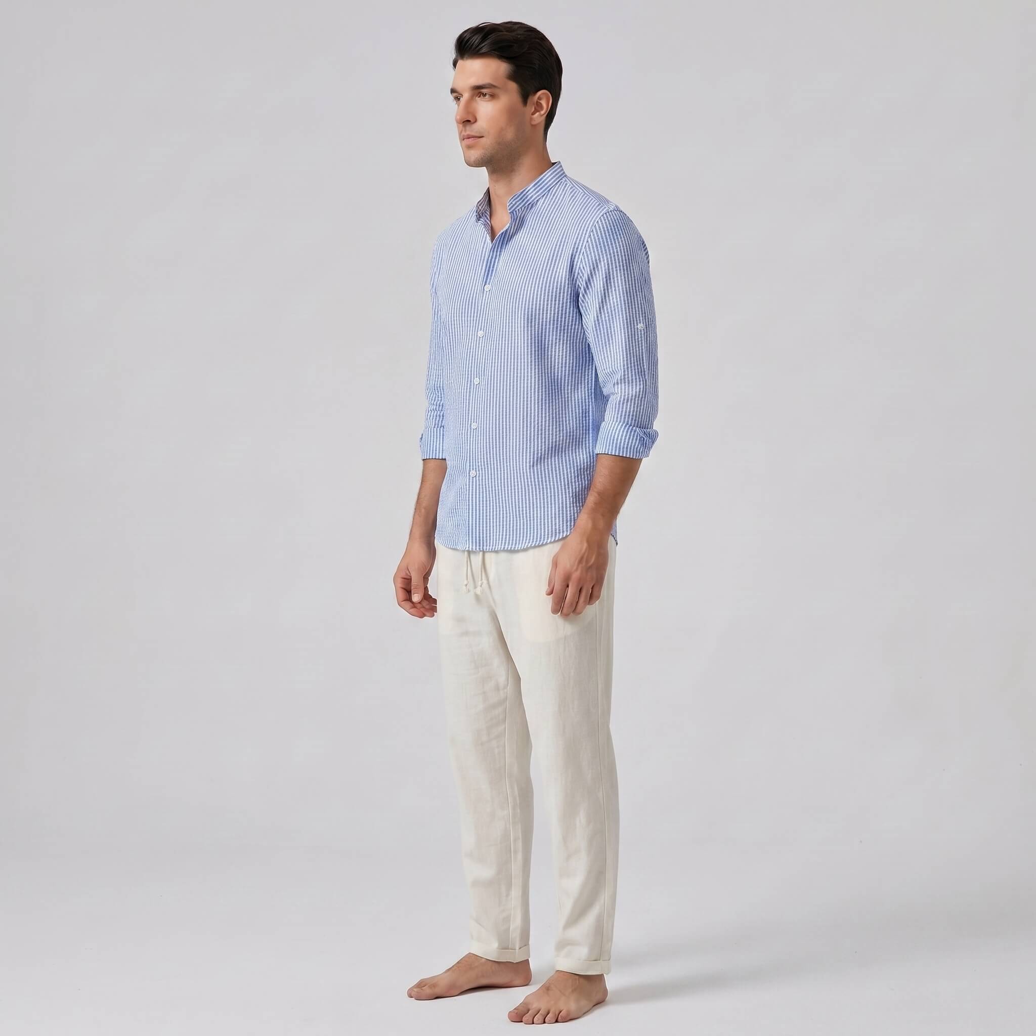 Man wearing a light blue striped shirt and white pants on a gray background