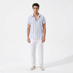 Man wearing a light blue striped shirt and white pants on a white background