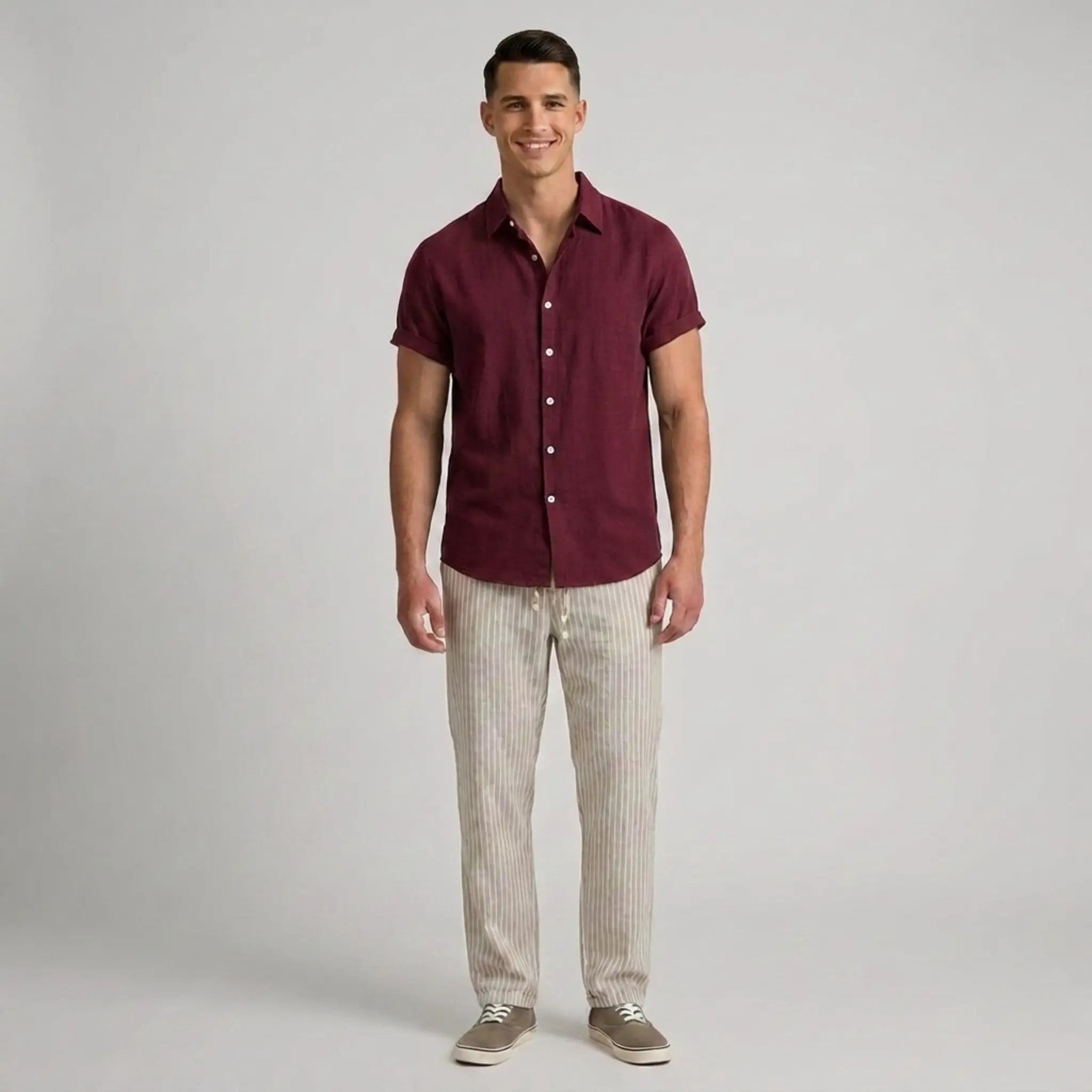 Man wearing a maroon button-up shirt and beige pants on a gray background