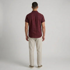 Man wearing a maroon polo shirt and beige striped pants on a gray background