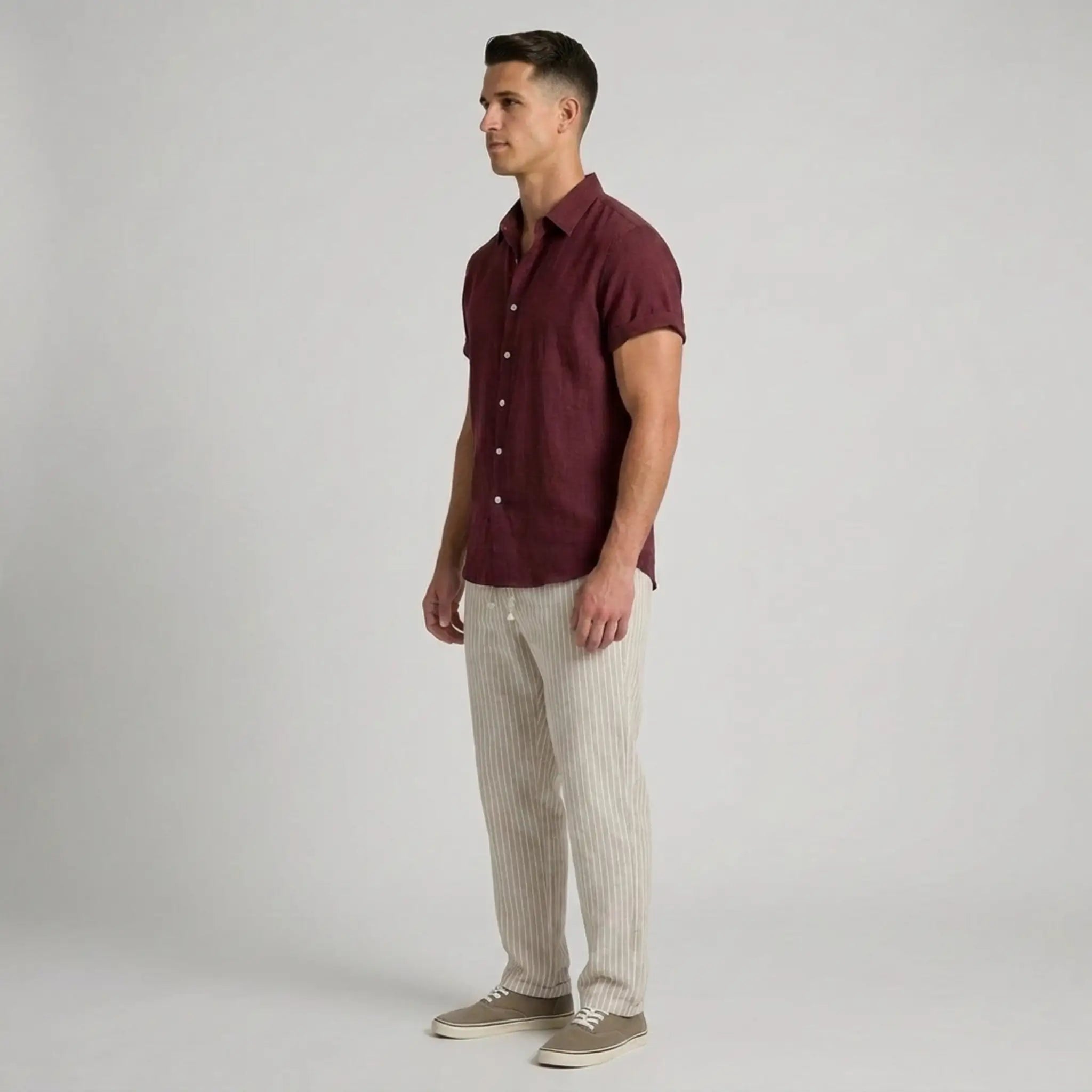 Man wearing a maroon shirt and beige pants on a gray background