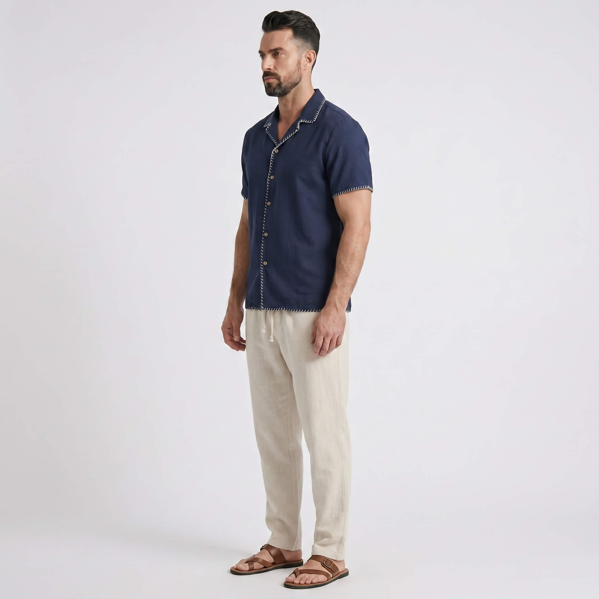 Man wearing a navy blue shirt and beige pants on a white background