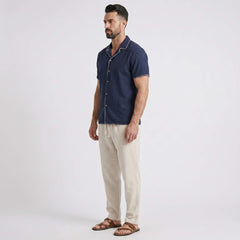 Man wearing a navy blue shirt and beige pants on a white background