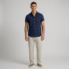 Man wearing a navy button-up shirt and beige striped pants on a gray background