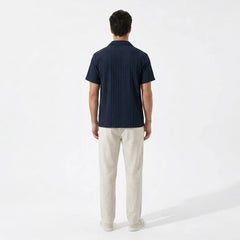 Man wearing a navy polo shirt and beige pants on a white background