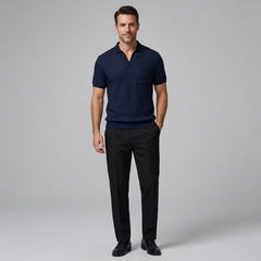 Man wearing a navy polo shirt and black pants on a gray background
